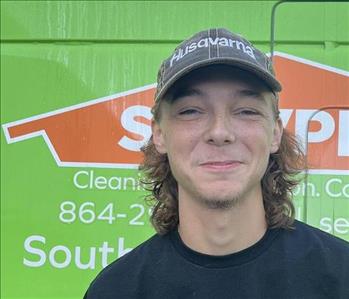 stryder (a man) standing in front of a green SERVPRO van
