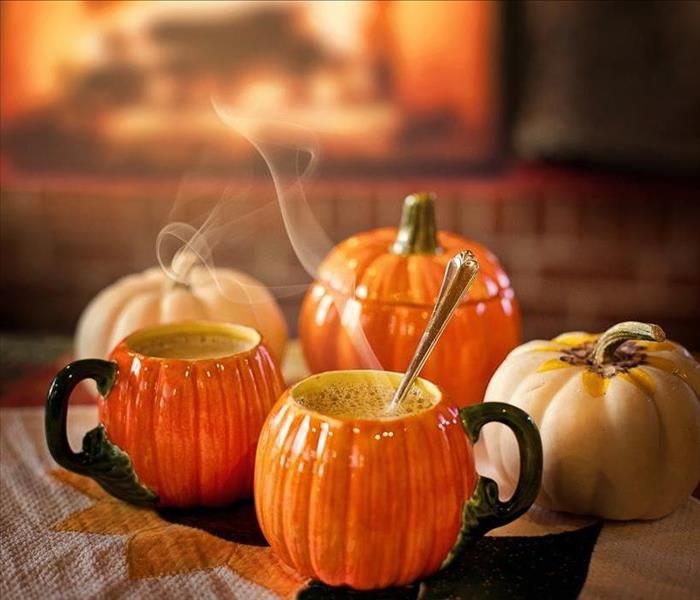 Pumpkin mugs on an ottoman in front of a fire. 